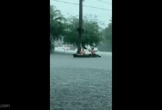 Hai người đàn ông chèo thuyền trên đường ngập nước giữa mưa lớn